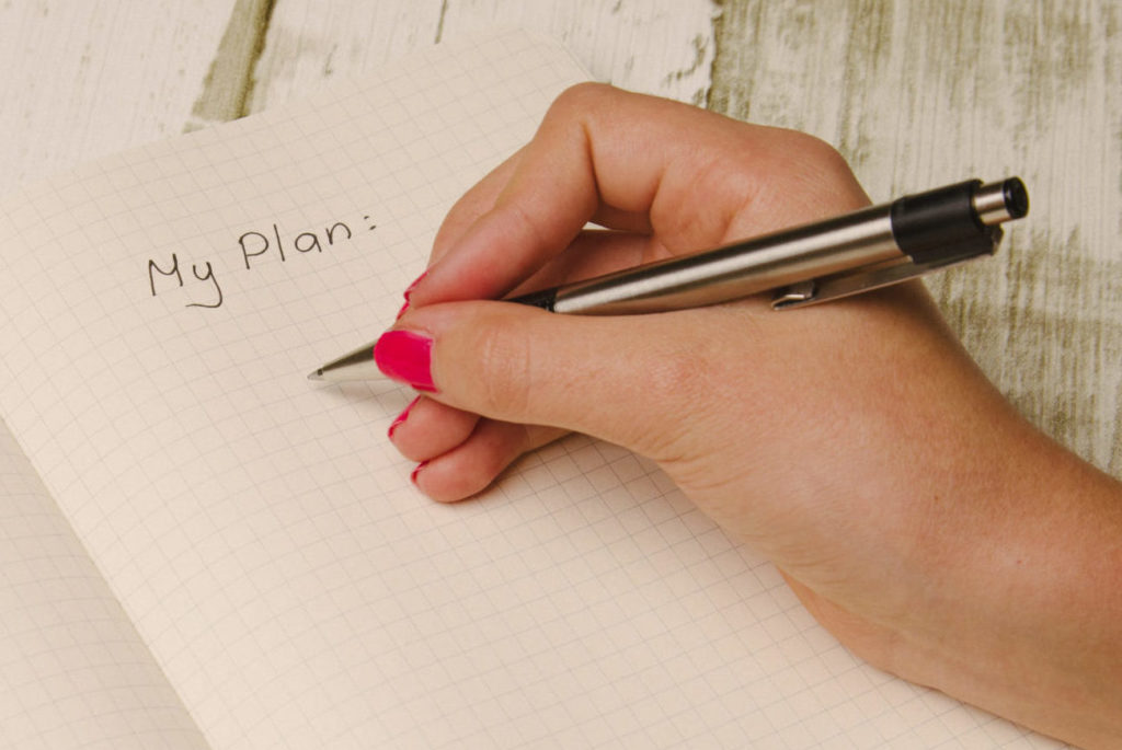 Female hand holding a pen and writing a plan in a planner